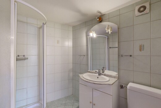 salle de bains avec tile wall, mur en carrelage, miroir, lavabo (ou coiffeuse selon le contexte), et douche