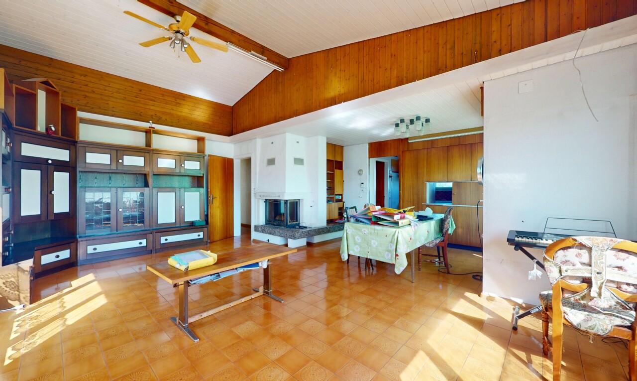 living / dining area with a ceiling fan and wooden walls