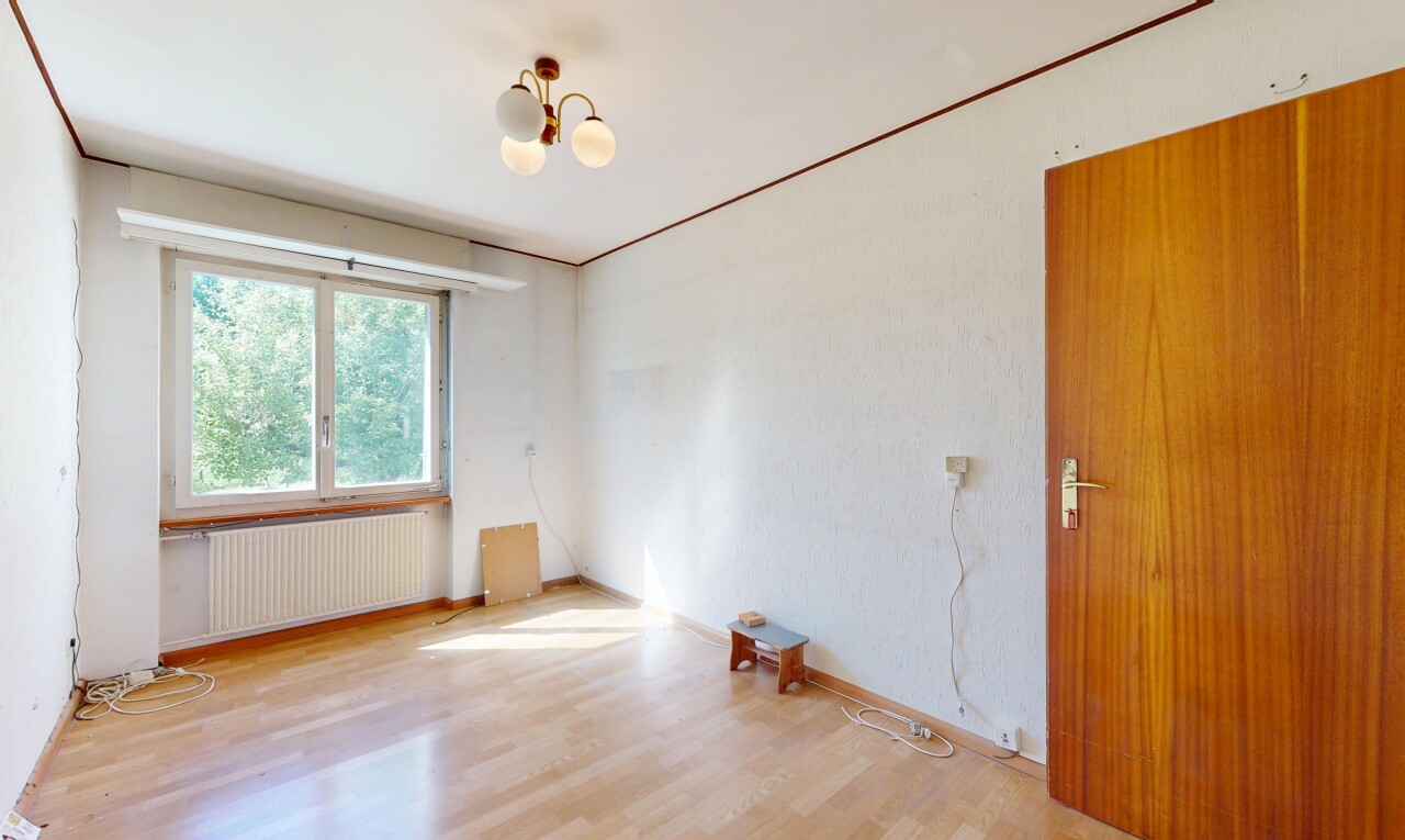empty room with radiator heating unit, a chandelier, and wood finished floors