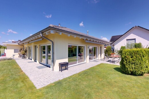 außenansicht mit terrasse, property visible, stuckverkleidung, rasen, und day time