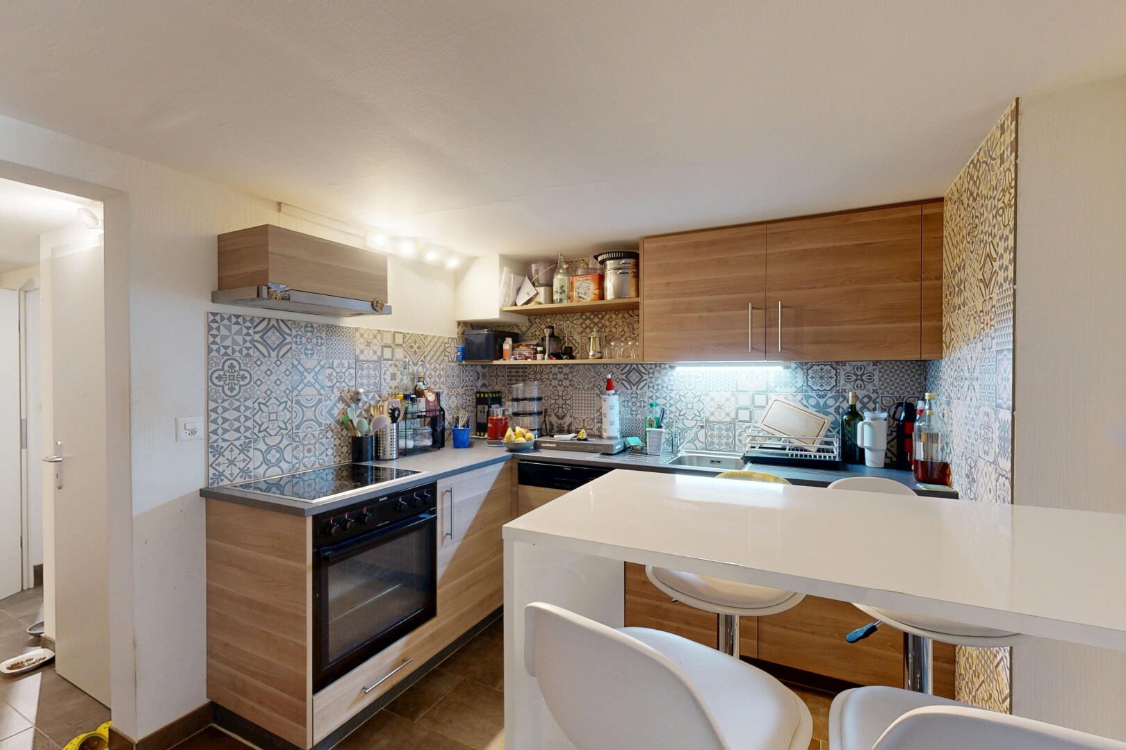 kitchen featuring modern cabinets, wood finish cabinets, decorative backsplash, open shelves, and a kitchen bar