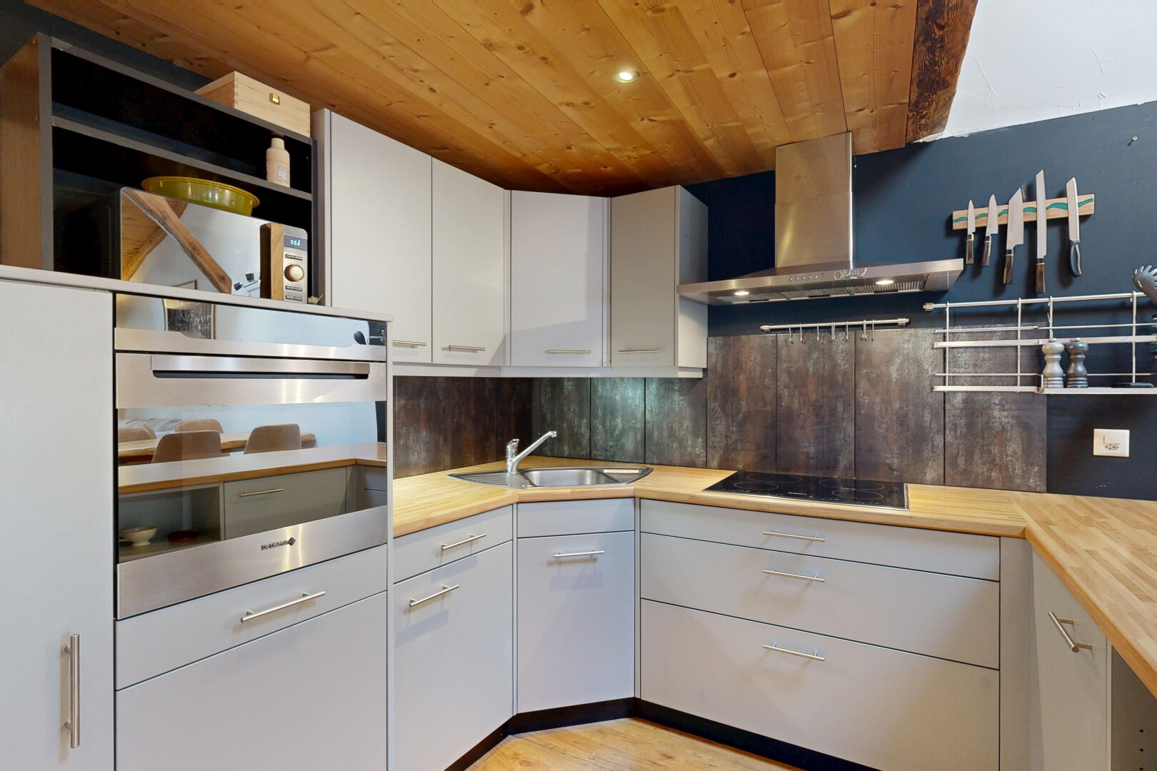 kitchen with stainless steel oven, wooden ceiling, white cabinets, open shelves, and backsplash