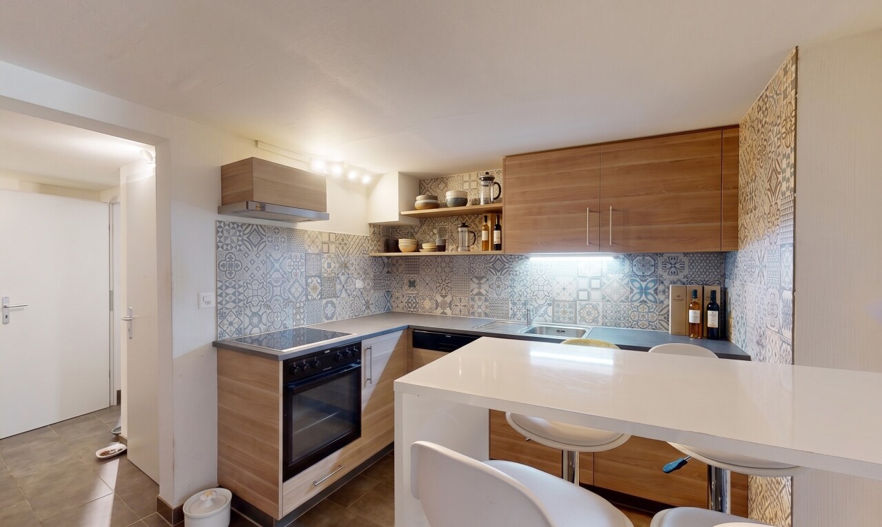 kitchen featuring modern cabinets, wood finish cabinets, decorative backsplash, open shelves, and a kitchen bar