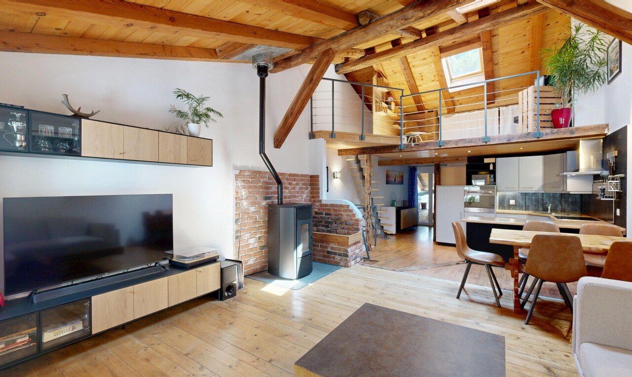 living area with a wood stove, light wood-type flooring, and a high wooden beamed ceiling