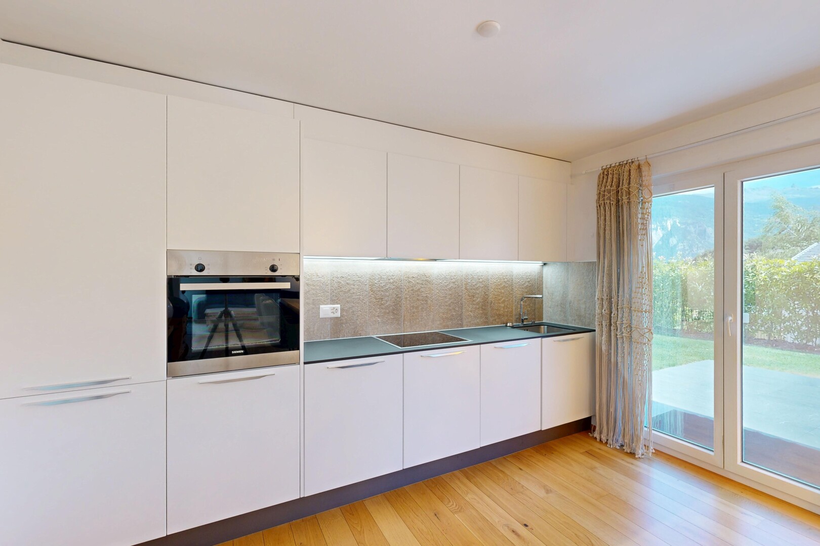 cuisine avec four, light floor, inside property, sol en finition bois, et wood finish floor