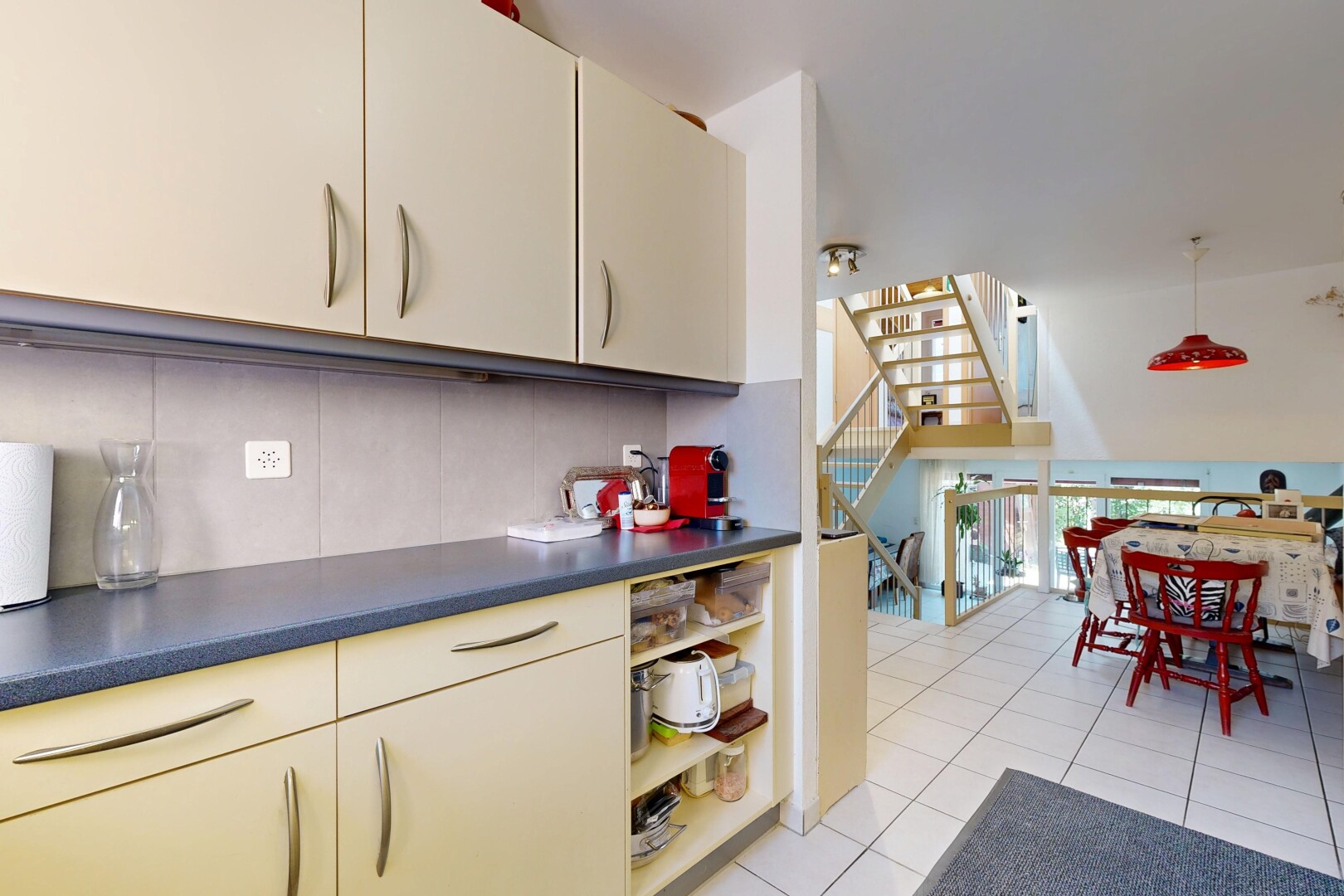 cuisine avec light floor, escaliers, dosseret, backsplash, et sol en carrelage