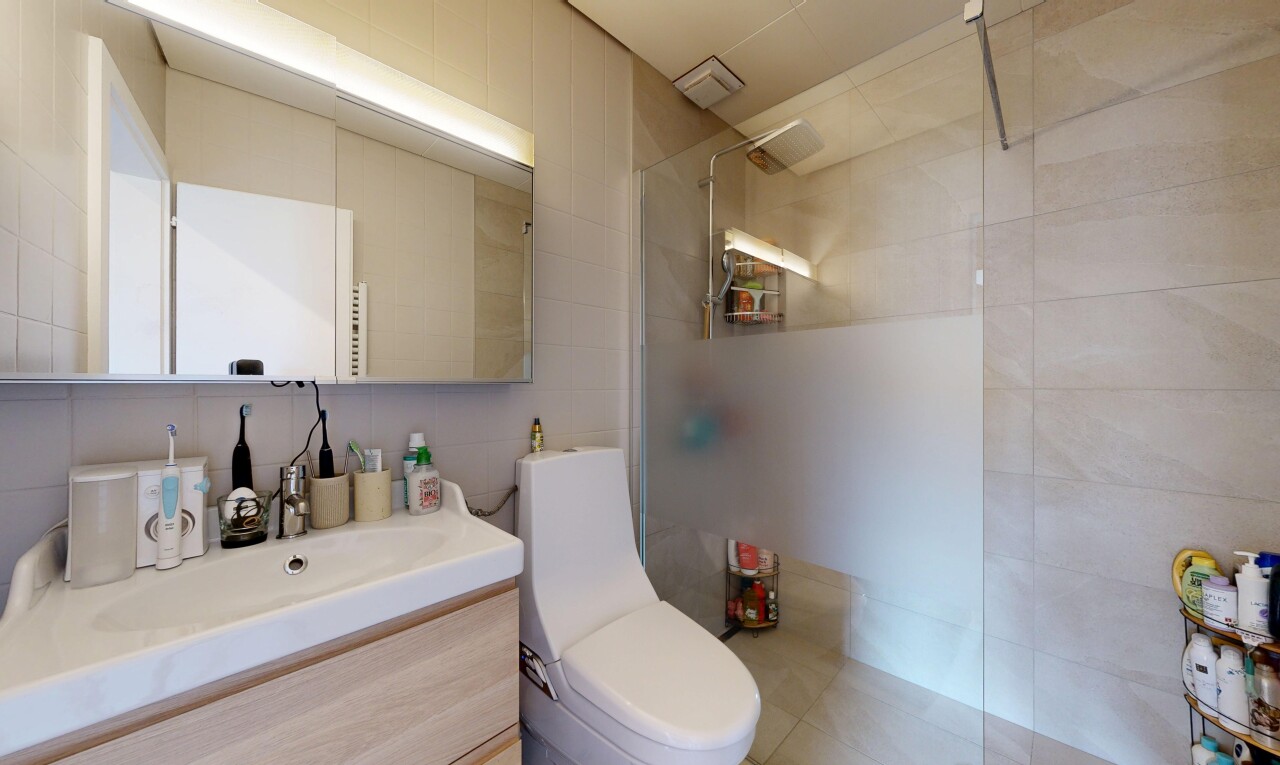 salle de bains avec douche, lavabo (ou coiffeuse selon le contexte), salle de bain complète, toilette, et mur en carrelage