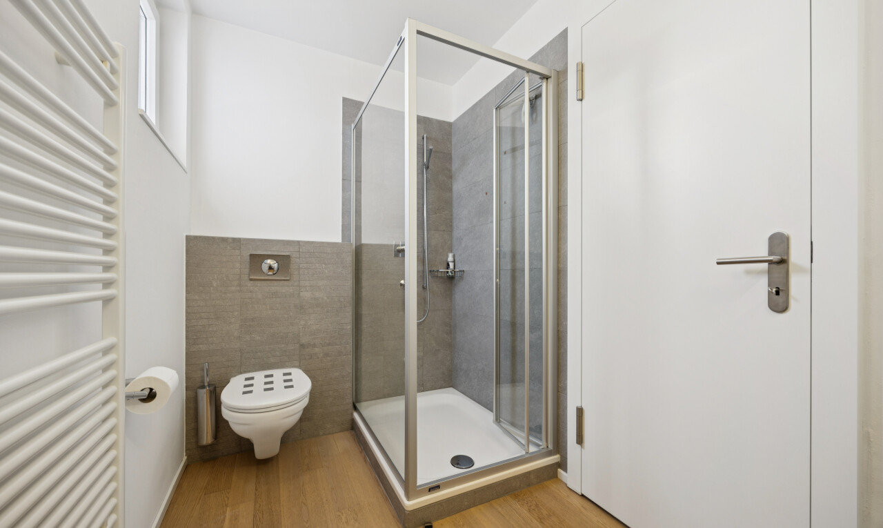 full bath featuring radiator, a stall shower, a towel warming rack, and light wood-type flooring