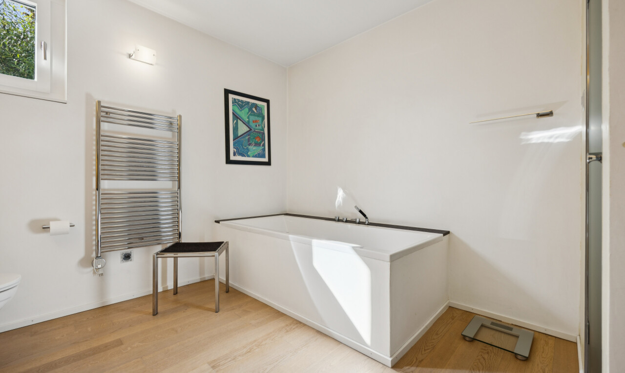full bath featuring radiator, a bath, light wood-type flooring, and a towel warming rack