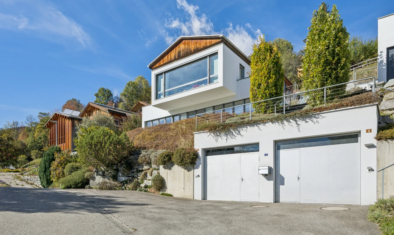 außenansicht mit garage, auffahrt, stuckverkleidung, property visible, und day time