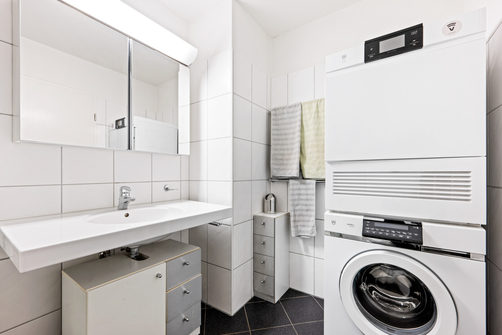 bathroom with stacked washer / dryer, dark tile patterned floors, tile walls, and backsplash