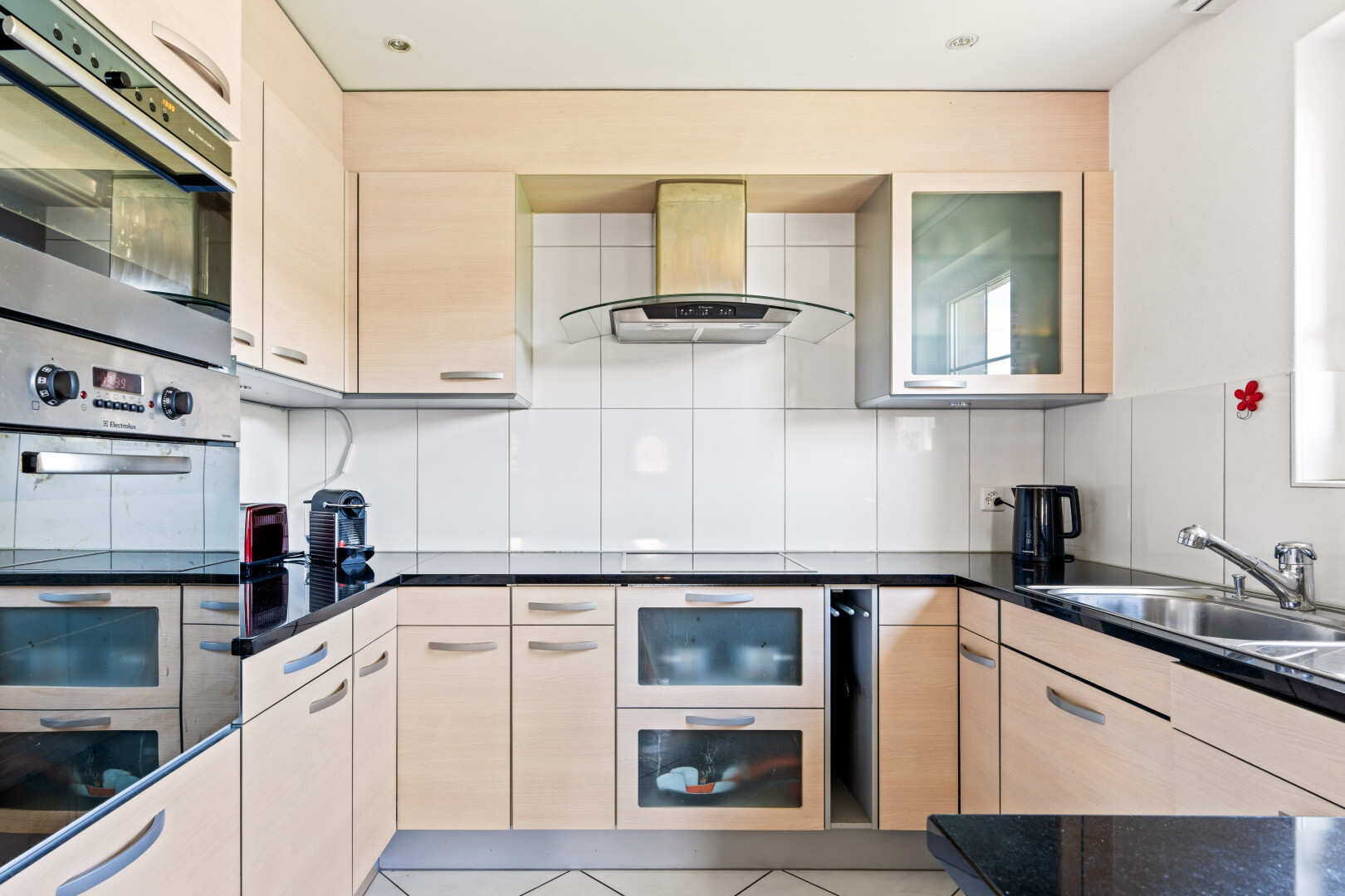 kitchen with island exhaust hood, double oven, decorative backsplash, light wood finish cabinetry, and light tile patterned floors