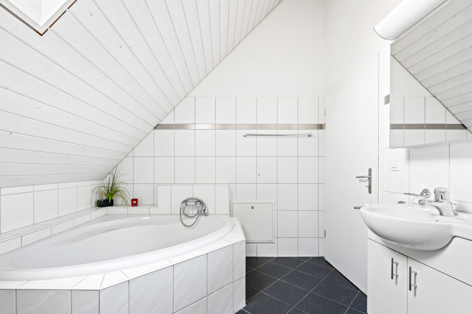 full bathroom featuring vanity, a bath, lofted ceiling, and dark tile patterned floors