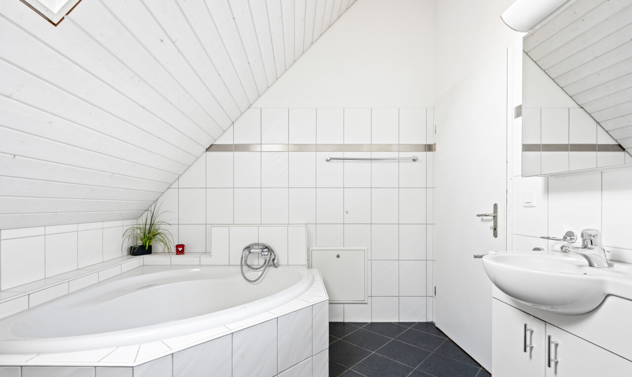 full bathroom featuring vanity, a bath, lofted ceiling, and dark tile patterned floors