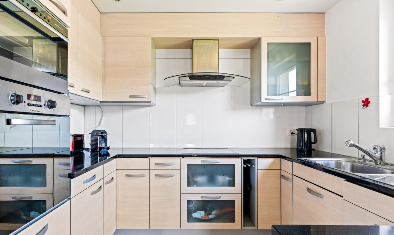 cuisine avec dark countertops, hotte, light floor, four double, et évier