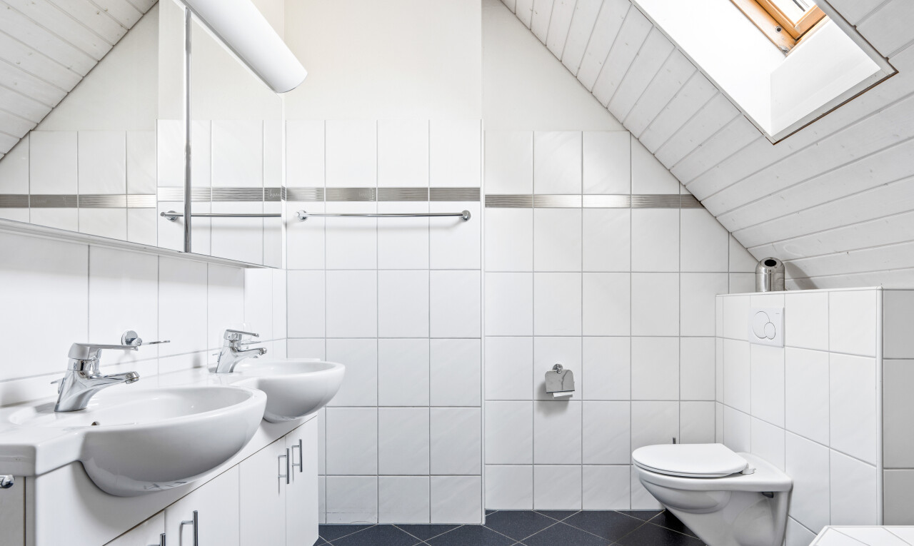 salle de bains avec mur en carrelage, tile wall, miroir, dark floor, et double vasque