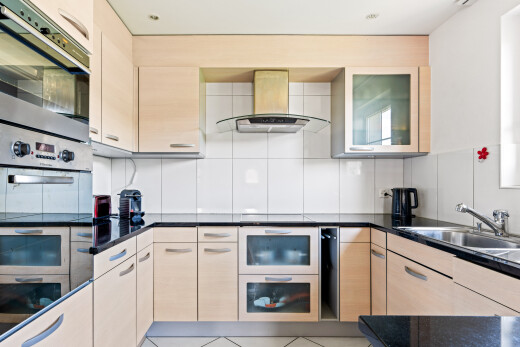 kitchen with island exhaust hood, double oven, decorative backsplash, light wood finish cabinetry, and light tile patterned floors