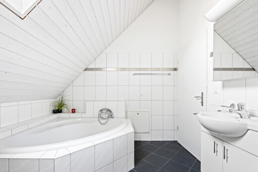full bathroom featuring vanity, a bath, lofted ceiling, and dark tile patterned floors