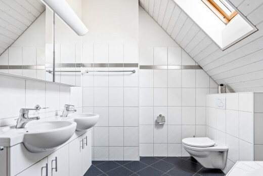 bathroom with tile walls, double vanity, dark tile patterned floors, vaulted ceiling, and a skylight