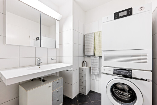 bathroom with stacked washer / dryer, dark tile patterned floors, tile walls, and backsplash