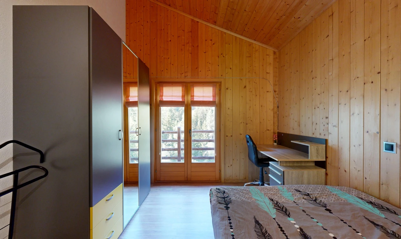 chambre avec vaulted ceiling, plafond voûté, wood wall, mur en bois, et espace bureau