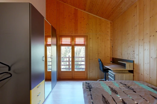 chambre avec vaulted ceiling, plafond voûté, wood wall, mur en bois, et espace bureau