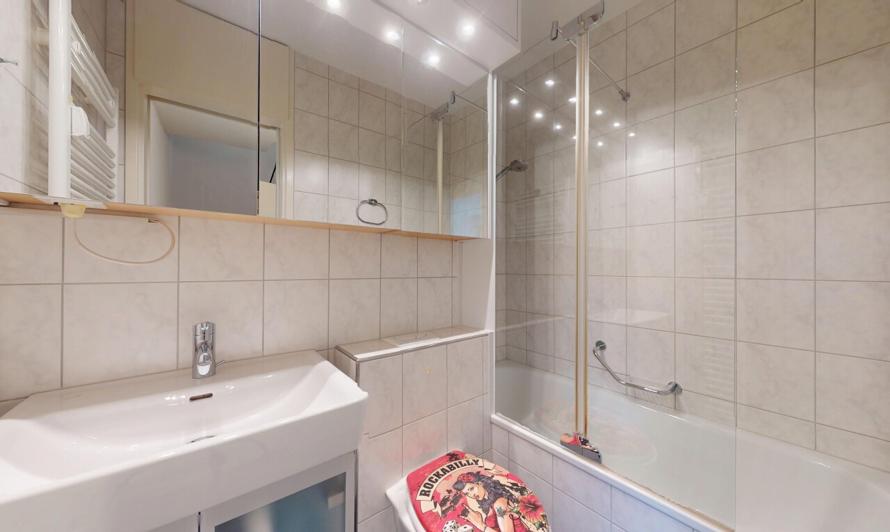 full bathroom featuring tile walls, tiled shower / bath combo, radiator heating unit, and a towel warmer