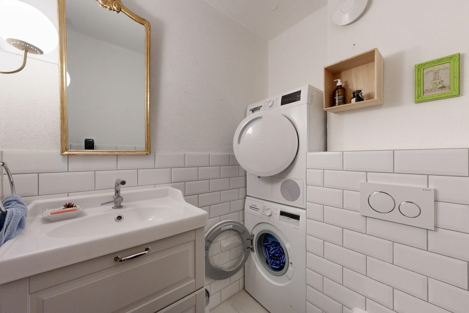 salle de bains avec miroir, lavabo (ou coiffeuse selon le contexte), mur en carrelage, tile wall, et lave-linge et sèche-linge superposés