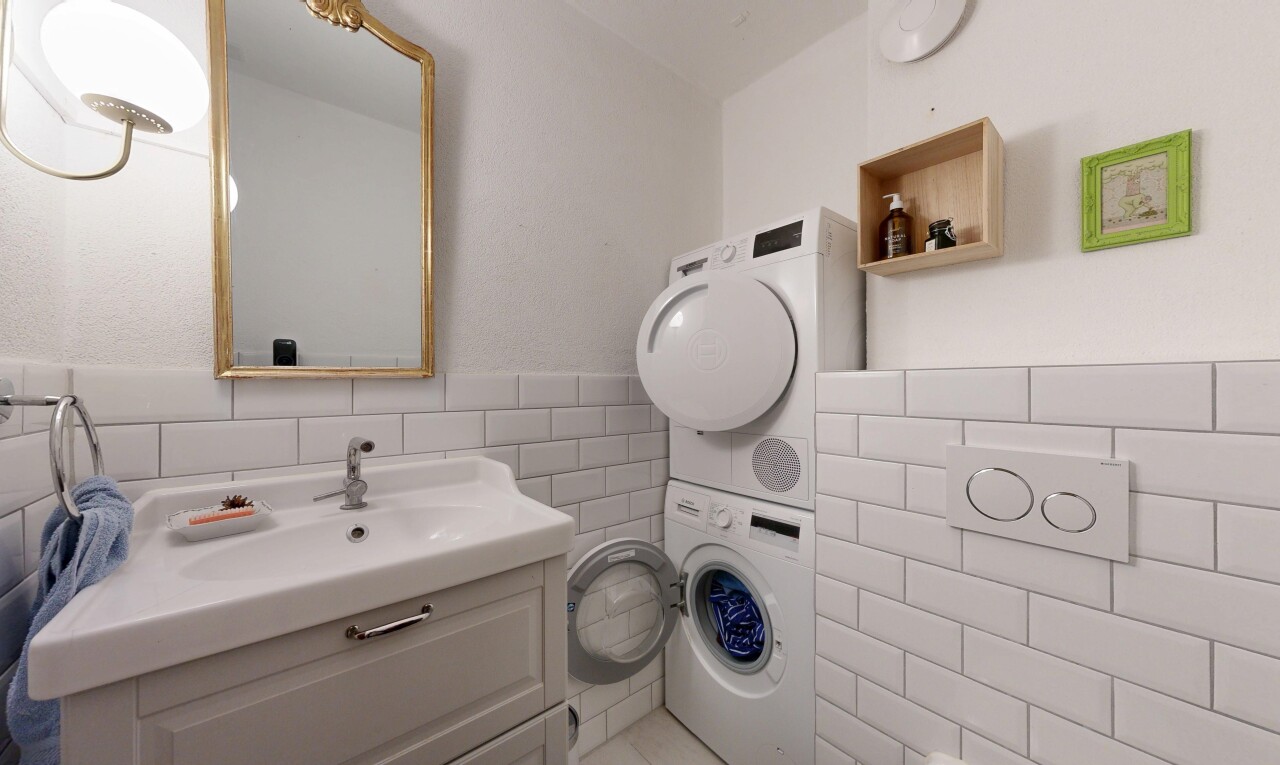 salle de bains avec miroir, lavabo (ou coiffeuse selon le contexte), mur en carrelage, tile wall, et lave-linge et sèche-linge superposés