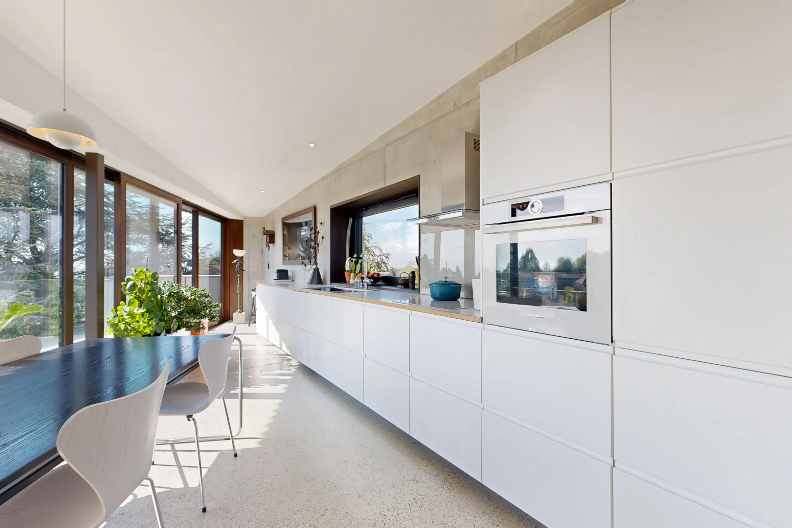 kitchen featuring hanging light fixtures, white oven, dark aggregate flooring, light countertops, and white cabinets