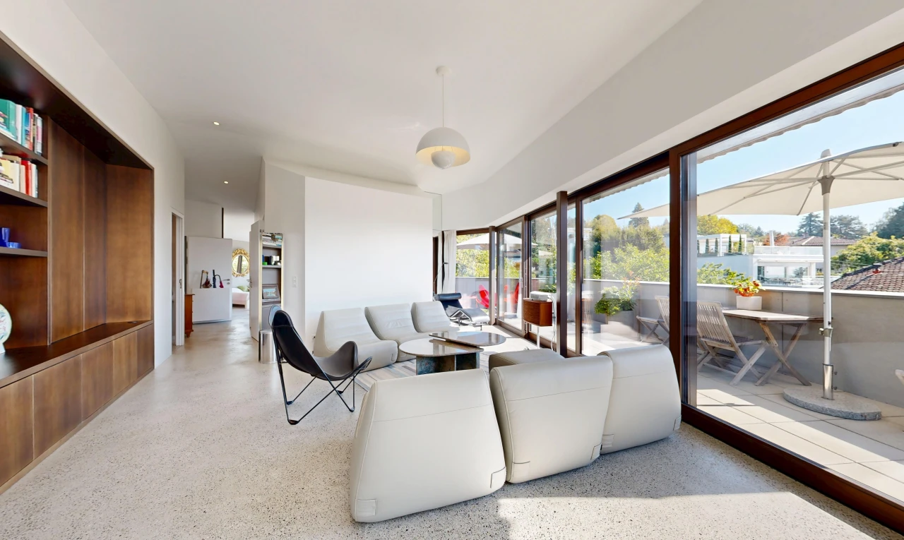 living area featuring dark aggregate flooring, hanging light fixtures, and access to exterior