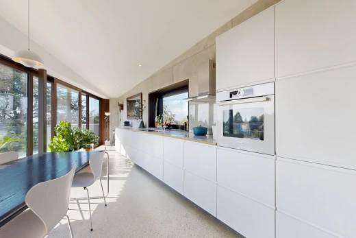 kitchen featuring hanging light fixtures, white oven, dark aggregate flooring, light countertops, and white cabinets