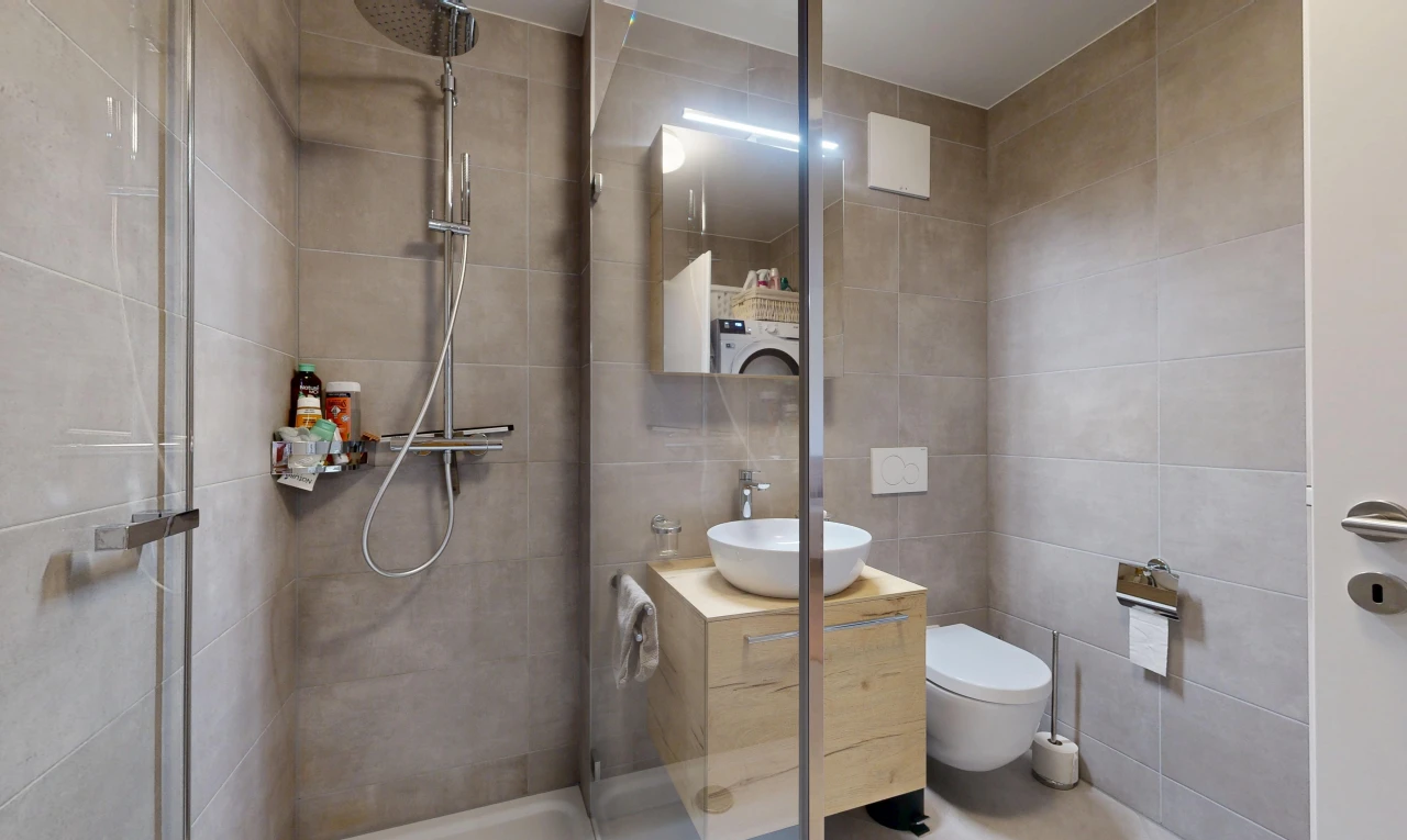 full bathroom featuring a shower stall, tile walls, vanity, and washer / dryer