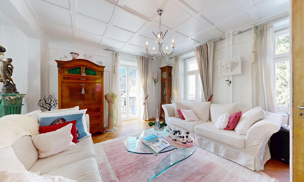 salon avec coffered ceiling, plafond à caissons, lustre remarquable, wood finish floor, et sol en finition bois