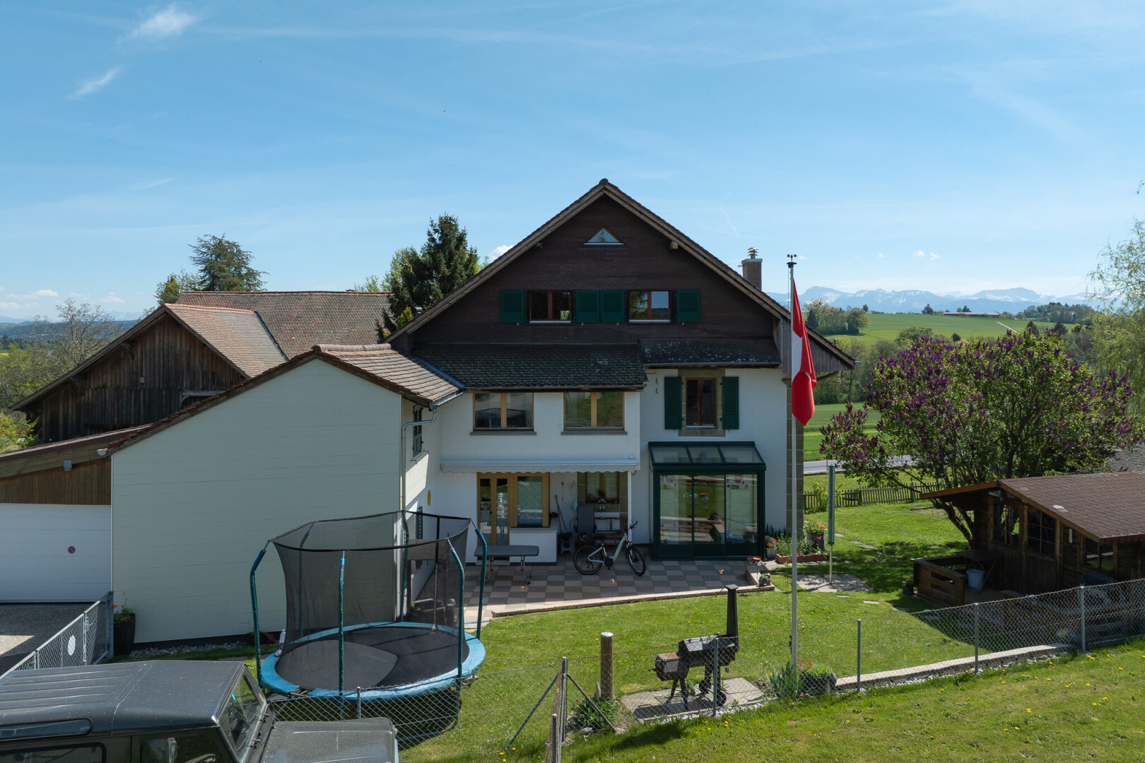 façade avec trampoline, terrasse, pelouse, clôture, et day time
