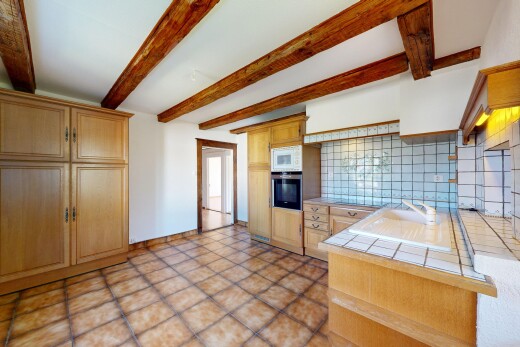 kitchen featuring tile countertops, decorative backsplash, oven, beam ceiling, and light wood finish cabinetry