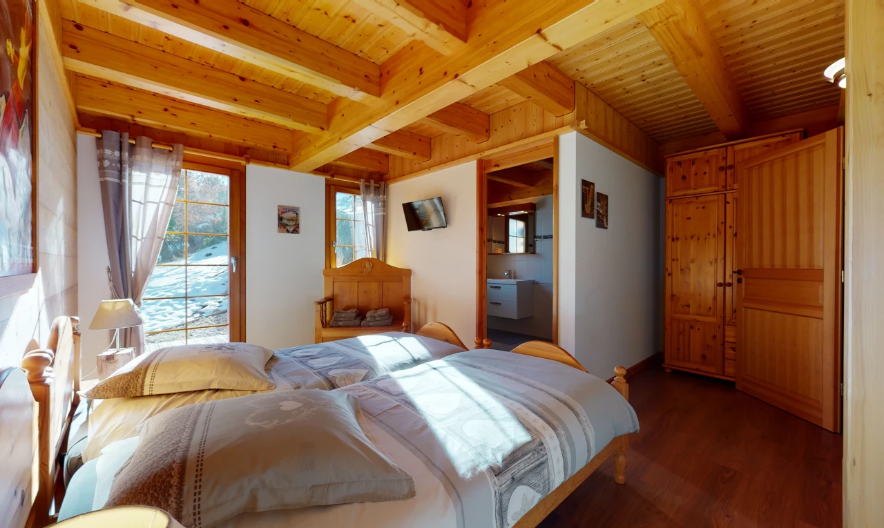 hartholzbodenschlafzimmer mit mehreren fenstern, holzbalkendecke und fernseher
