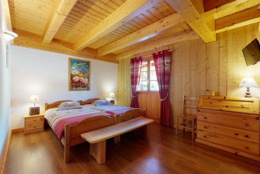 chambre à coucher avec poutres apparentes, lumière naturelle, parquet, et télévision