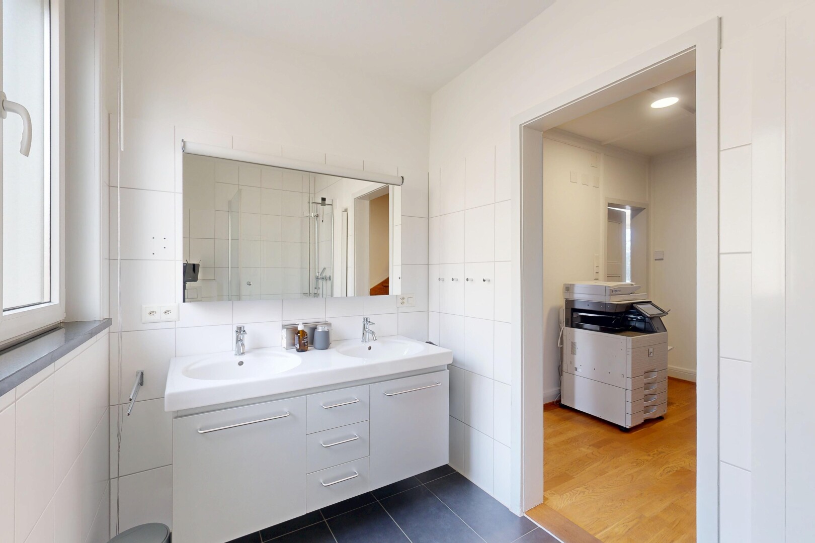 full bath featuring double vanity, dark tile patterned floors, tile walls, and tiled shower