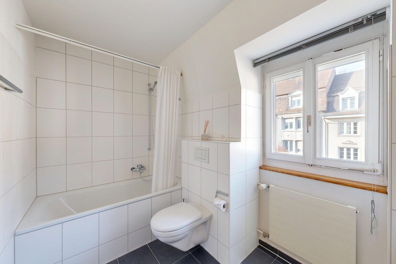 bathroom featuring radiator heating unit, tiled shower / bath, tile walls, and dark tile patterned floors