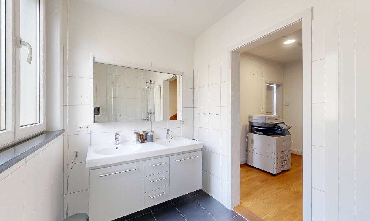 full bath featuring double vanity, dark tile patterned floors, tile walls, and tiled shower