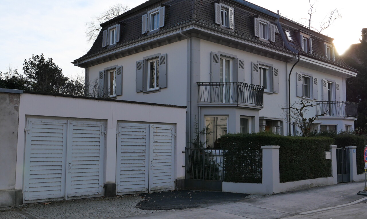 view of home with mansard roof, stucco siding, a balcony, and a fenced front yard