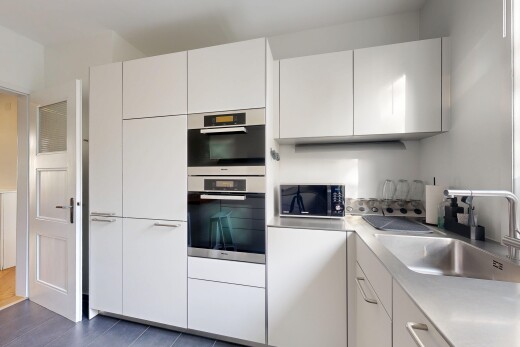 küche mit arbeitsplatten, weiße schränke, waschbecken, mikrowelle, und inside property