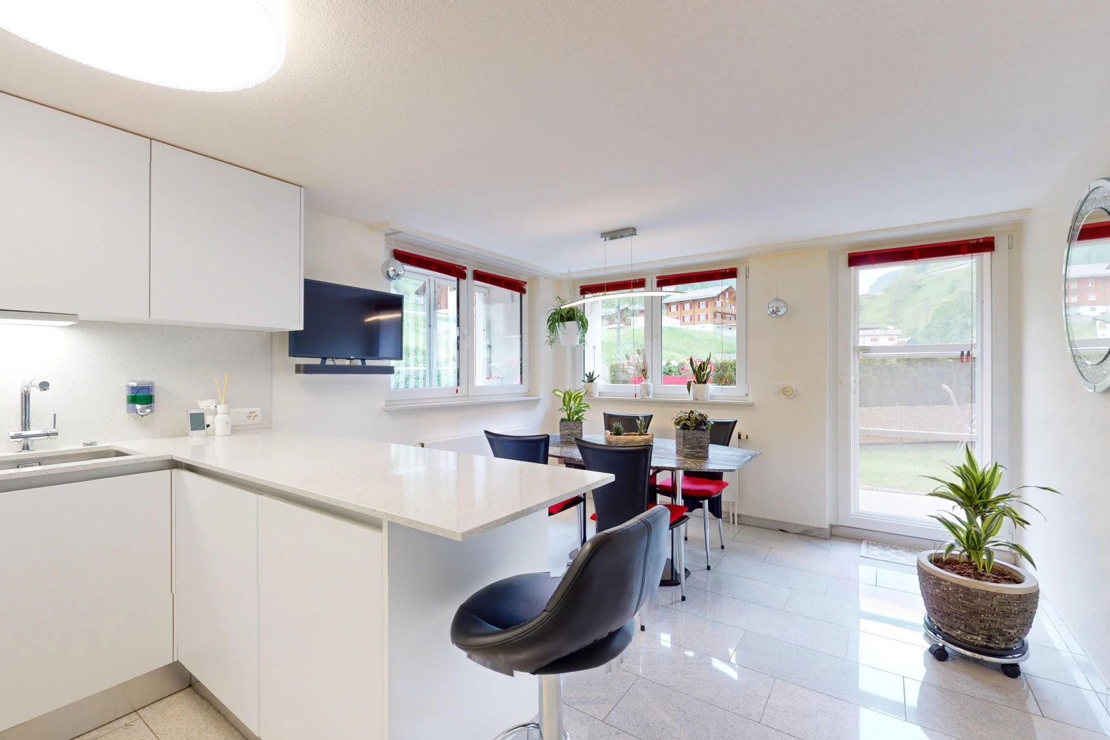 cuisine avec lumière naturelle, carrelage, meubles blancs, plan de travail, et télévision