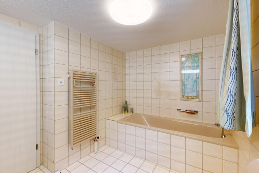 salle de bain avec radiateur, plafond en crépis, baignoire, et mur carrelé