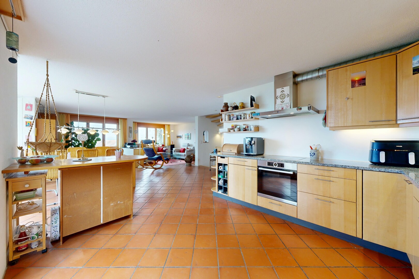 kitchen featuring light wood finish cabinets, stainless steel oven, open floor plan, hanging light fixtures, and open shelves