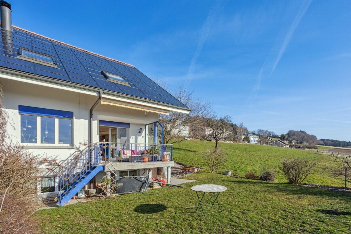 view of property featuring a lawn, roof mounted solar panels, and a wooden deck
