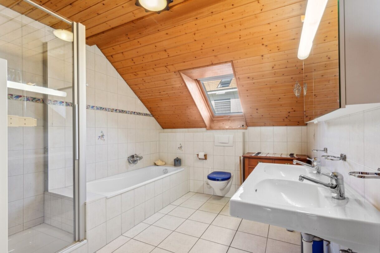 full bath featuring a garden tub, a shower stall, light tile patterned floors, tile walls, and a skylight