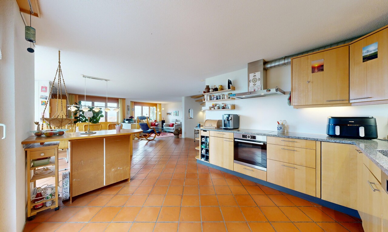 kitchen featuring light wood finish cabinets, stainless steel oven, open floor plan, hanging light fixtures, and open shelves
