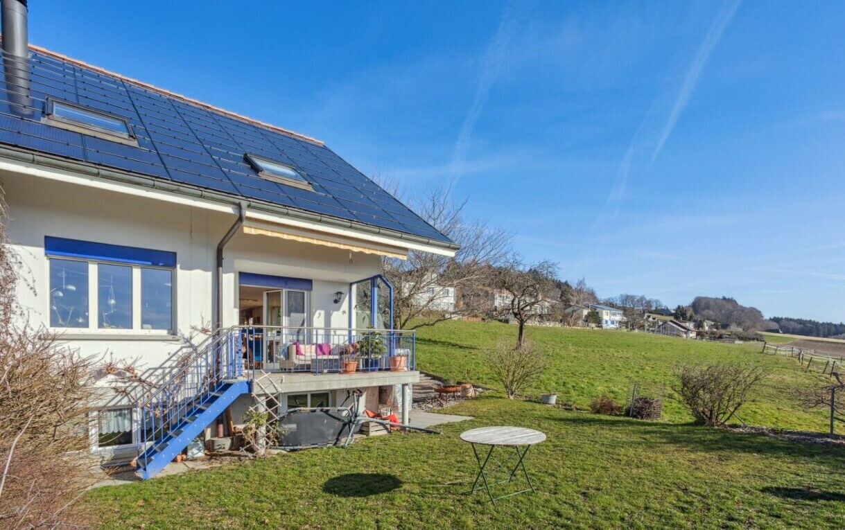 view of property featuring a lawn, roof mounted solar panels, and a wooden deck